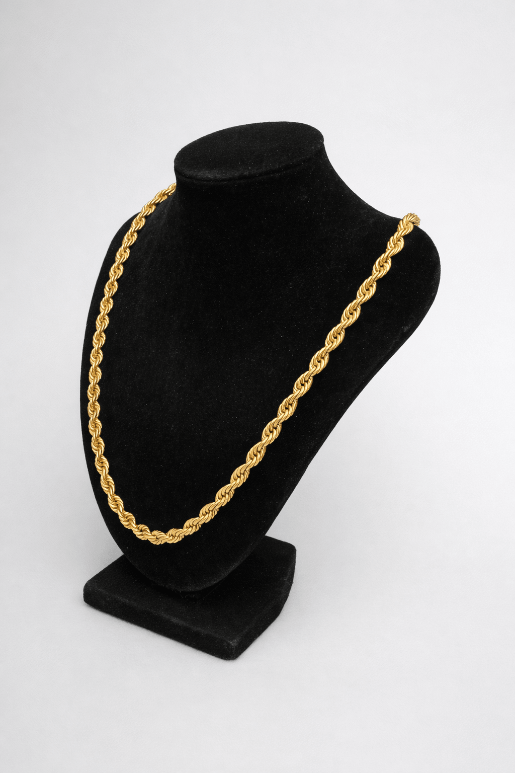 Gold chain necklace on a black mannequin bust against a white background