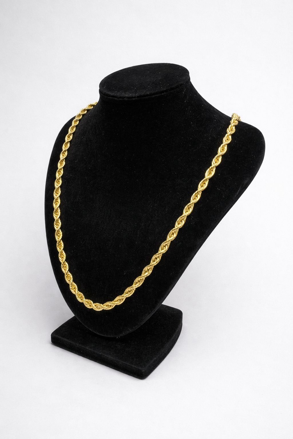 Gold chain necklace on a black mannequin bust against a white background