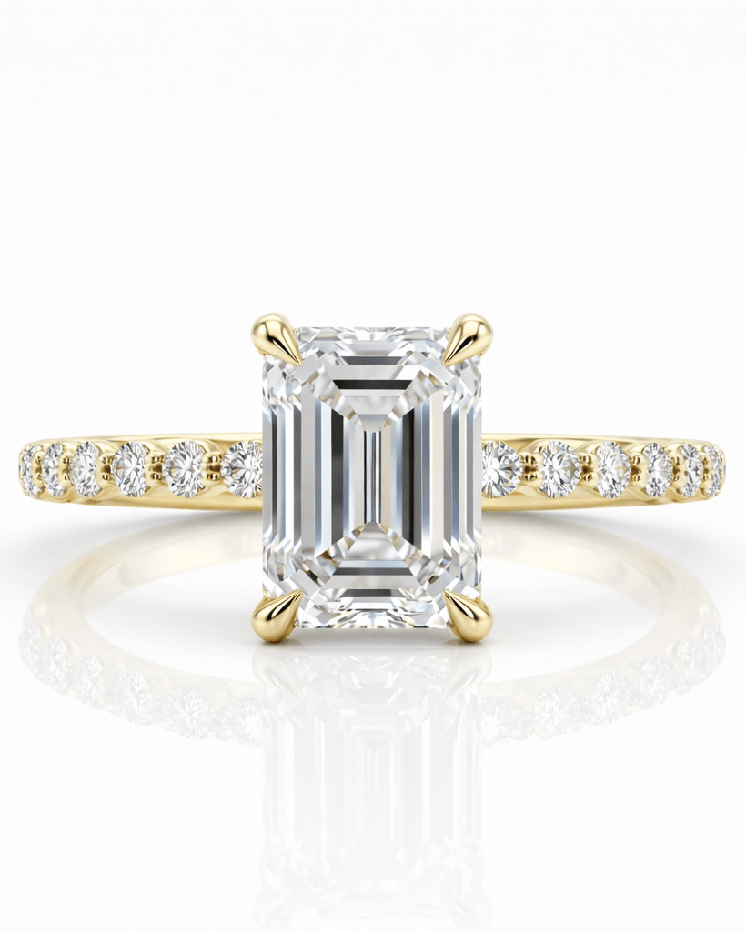 Gold ring with a large emerald-cut diamond and smaller diamonds on the band against a white background