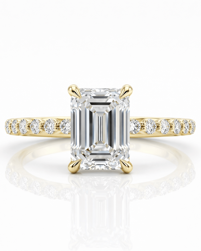 Gold ring with a large emerald-cut diamond and smaller diamonds on the band against a white background
