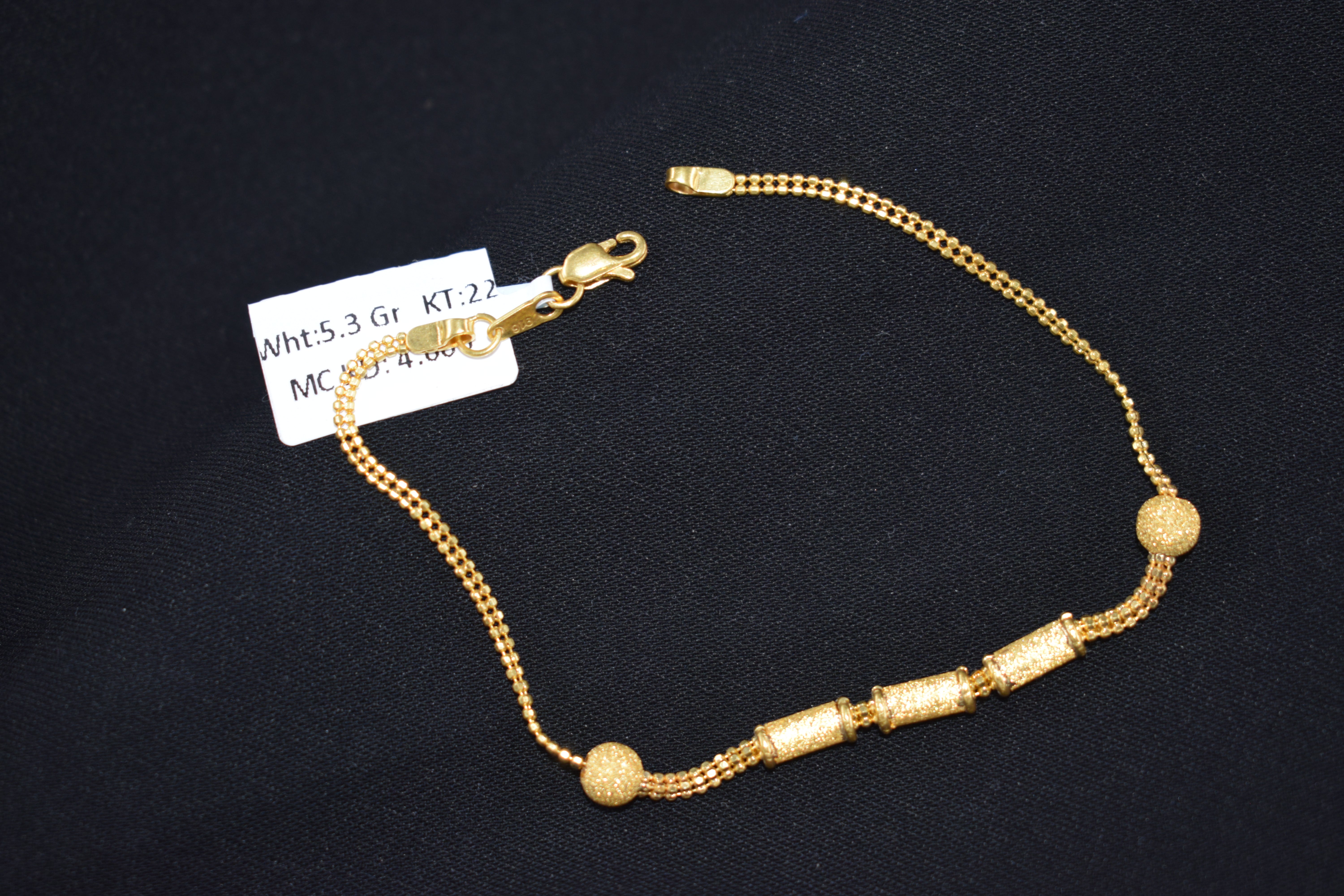 Gold bracelet with a tag on a black background