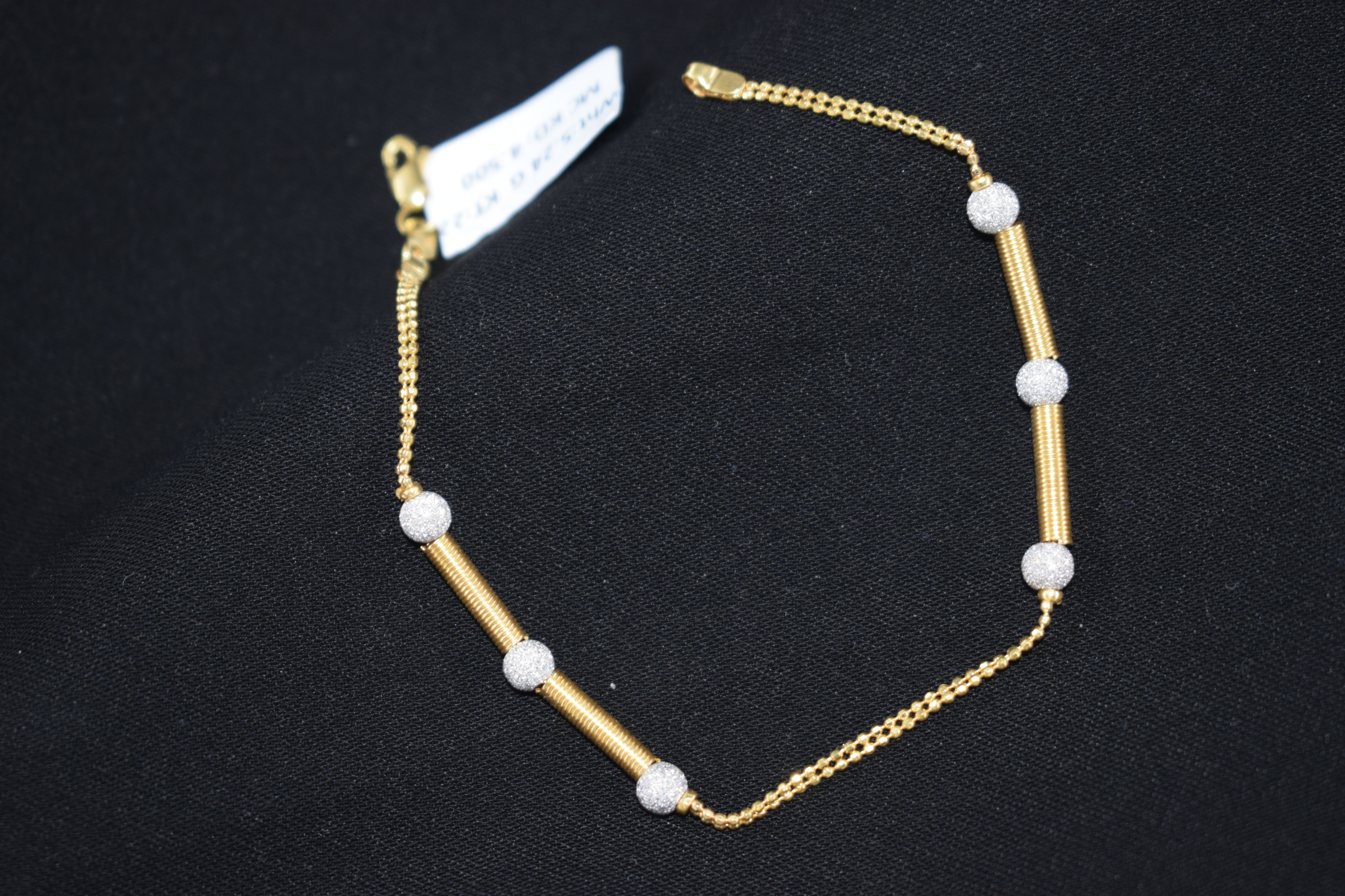 Gold bracelet with white beads on a black background