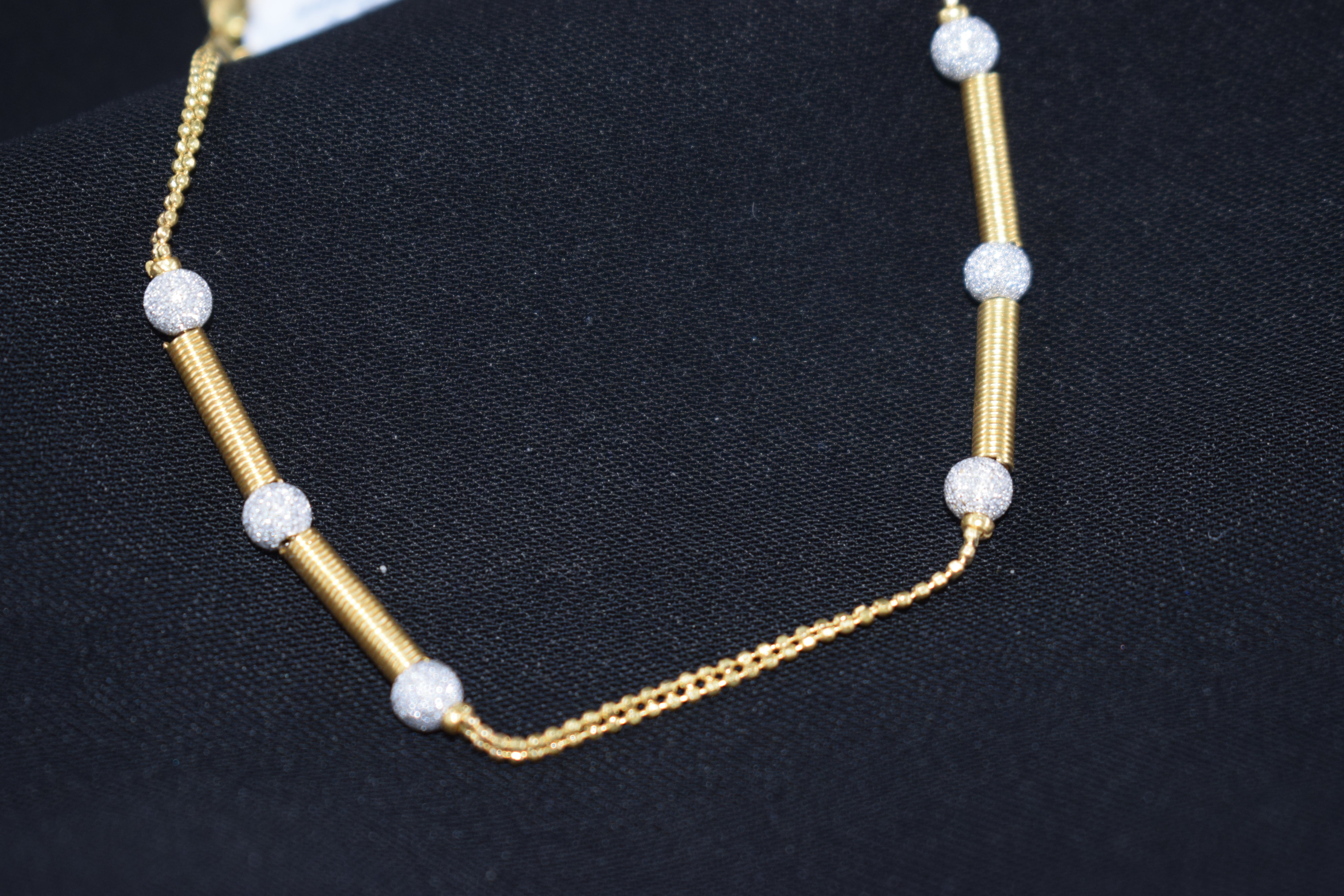 Gold necklace with white beads on a black background
