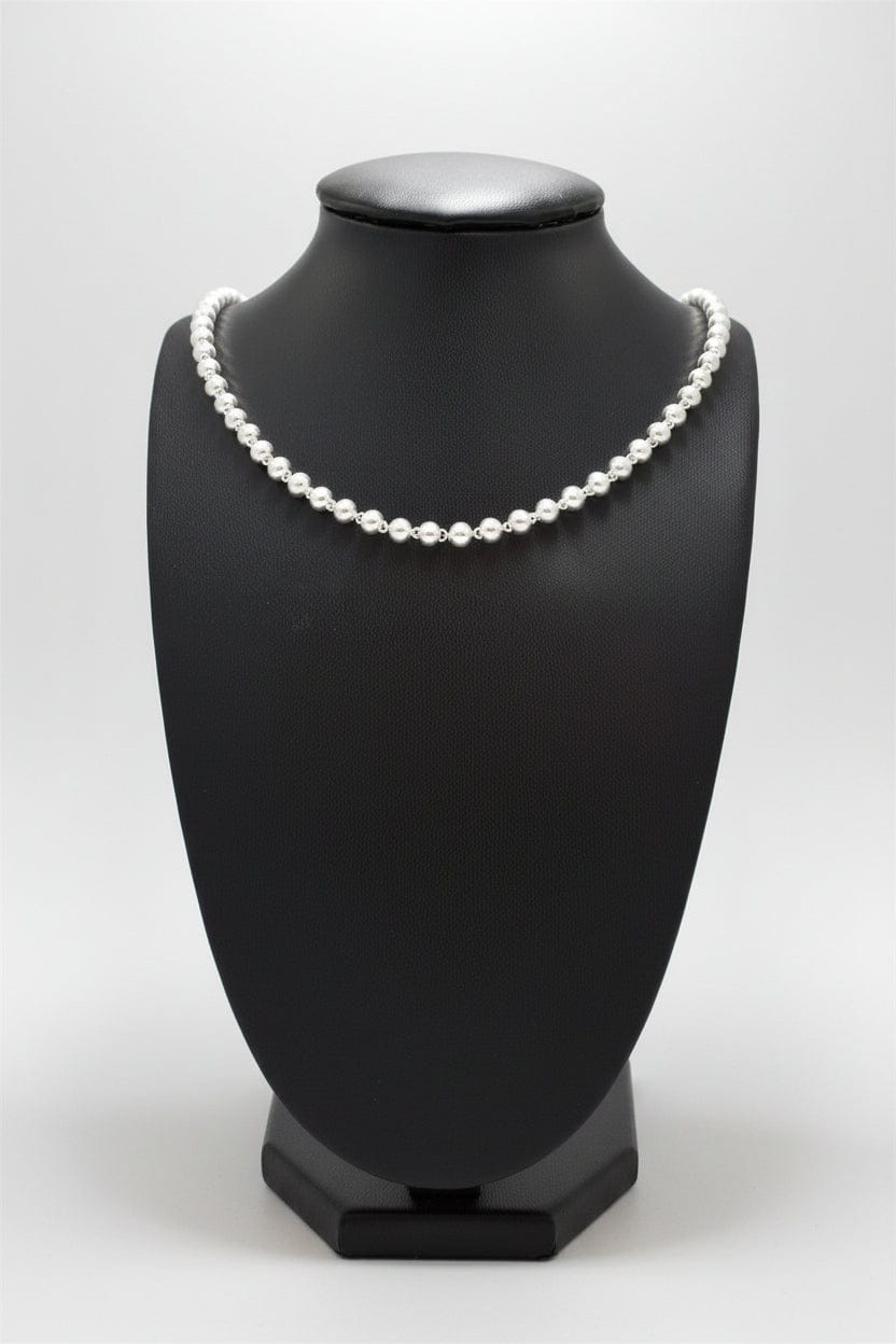 Pearl necklace on a black mannequin bust against a white background
