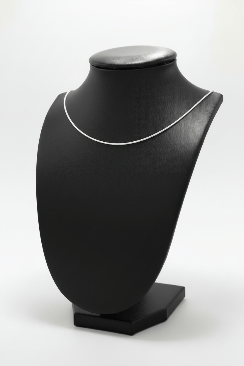 Silver necklace on a black mannequin with a white background