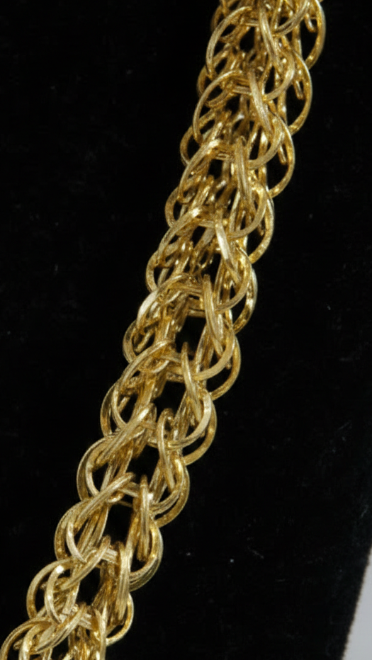 Gold chain necklace on a black stand with a white background