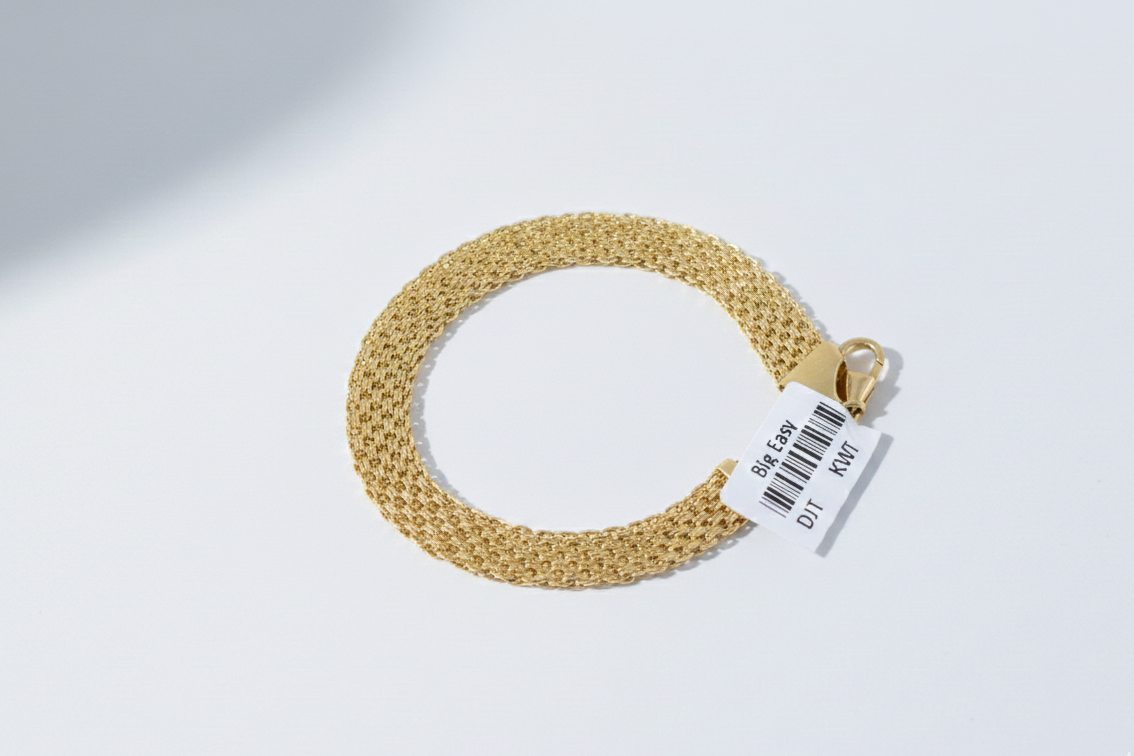 Gold bracelet on a light gray background with a visible brand tag.