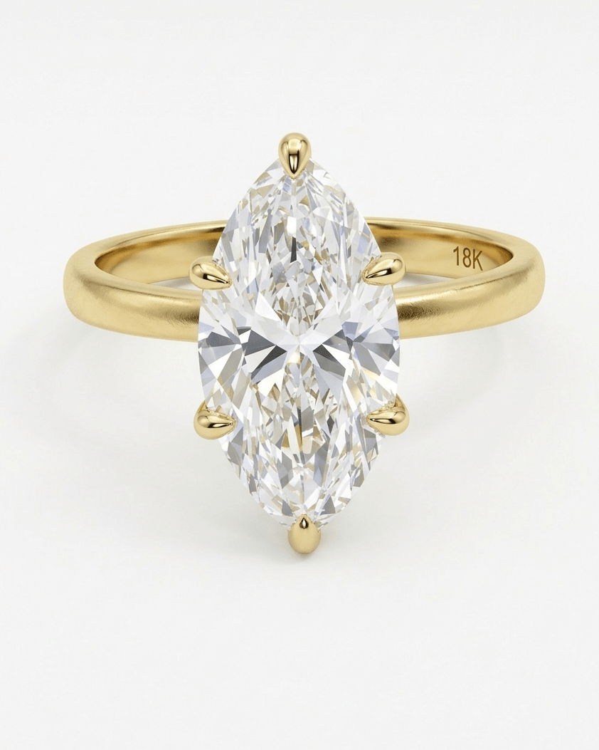 Gold ring with a pear-shaped diamond on a white background