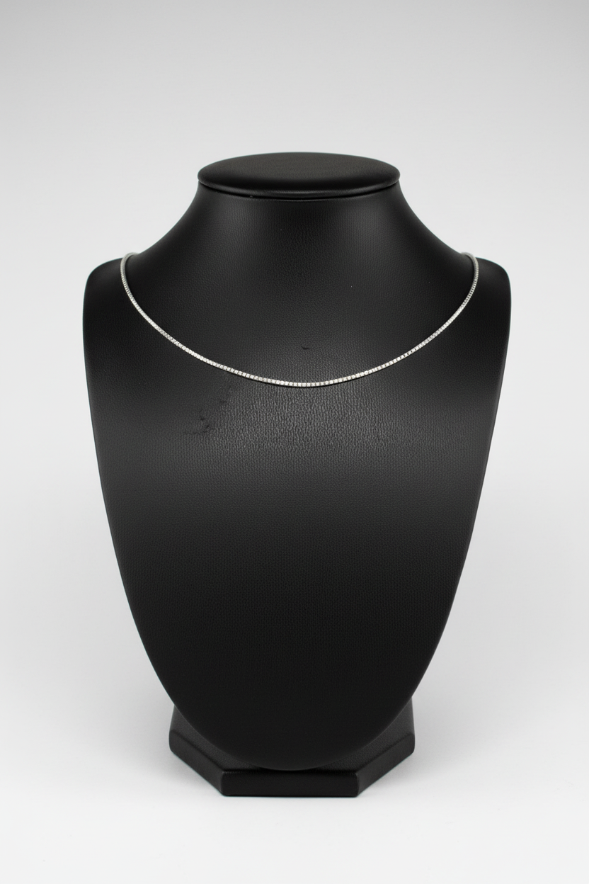 Silver necklace on a black mannequin bust against a white background