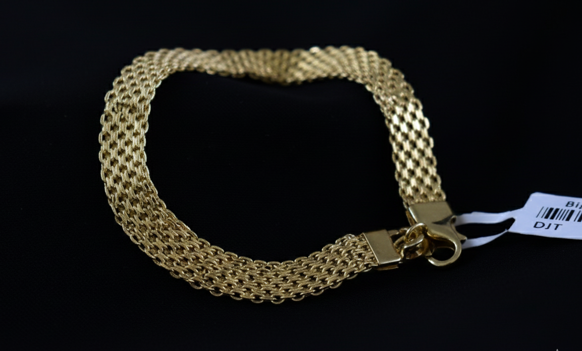 Gold chain bracelet on a black background with a visible brand label.