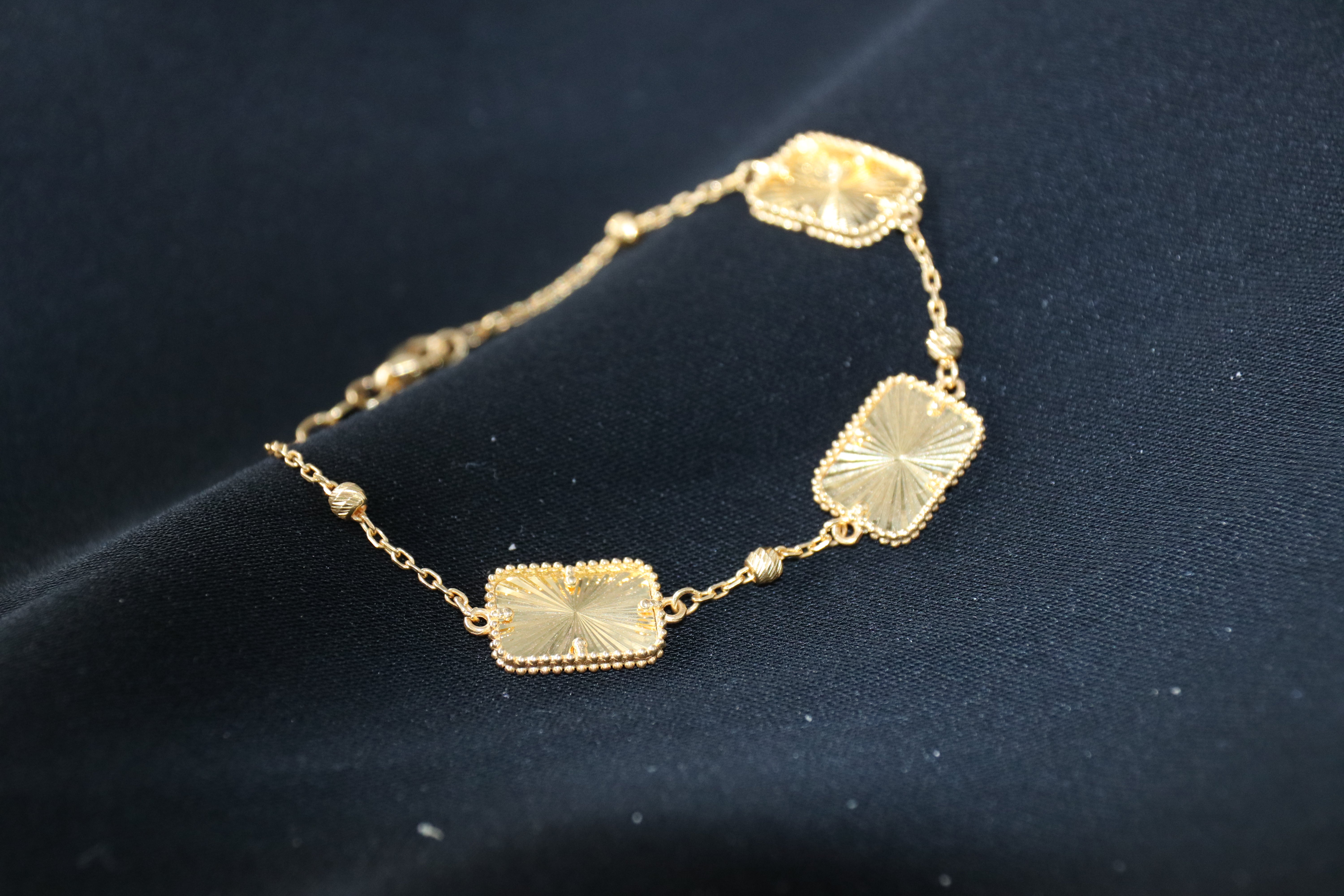 Gold bracelet with geometric designs on a dark background