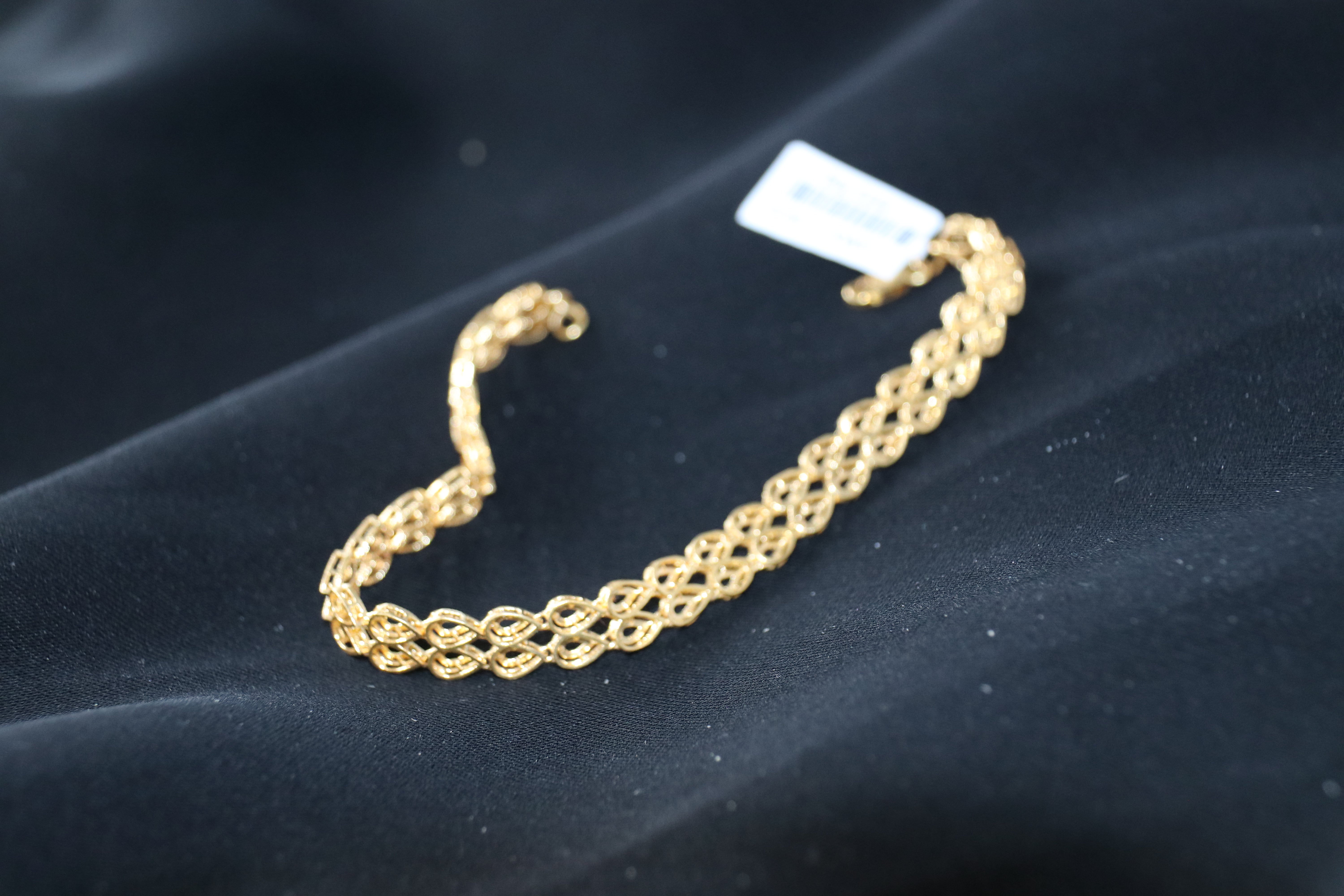 Gold bracelet on a dark fabric background
