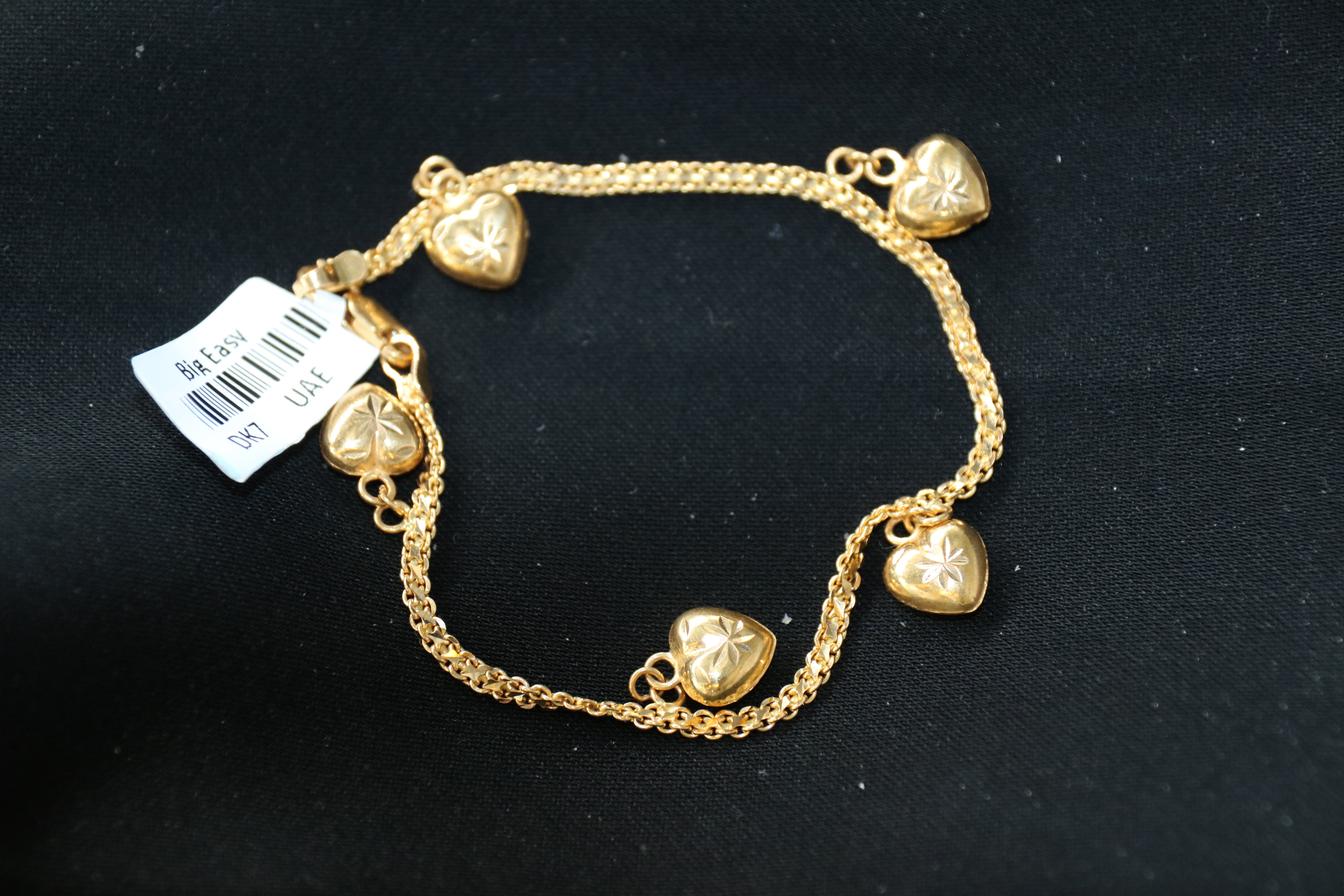 Gold bracelet with heart charms on a black background