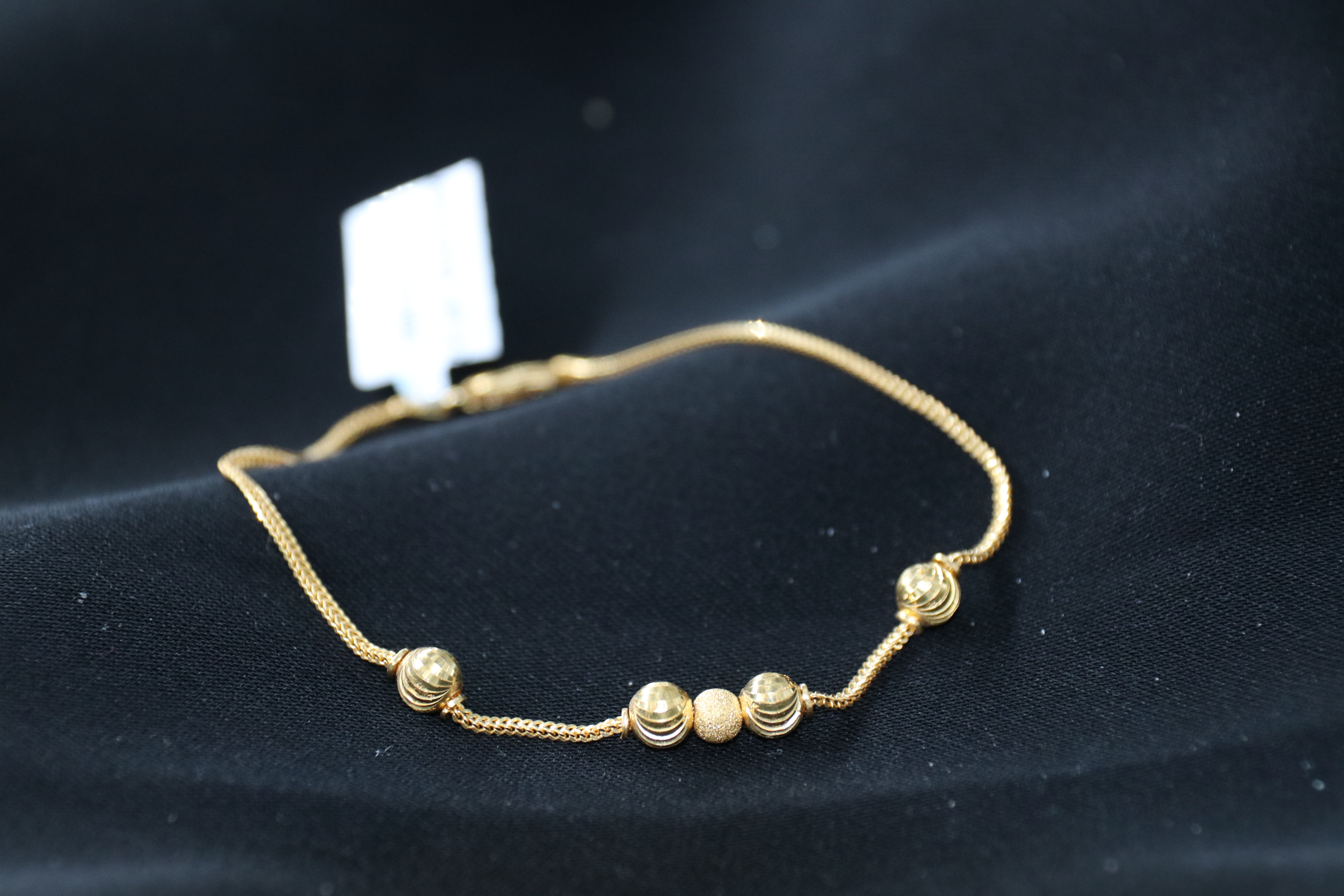 Gold bracelet with beads on a black background