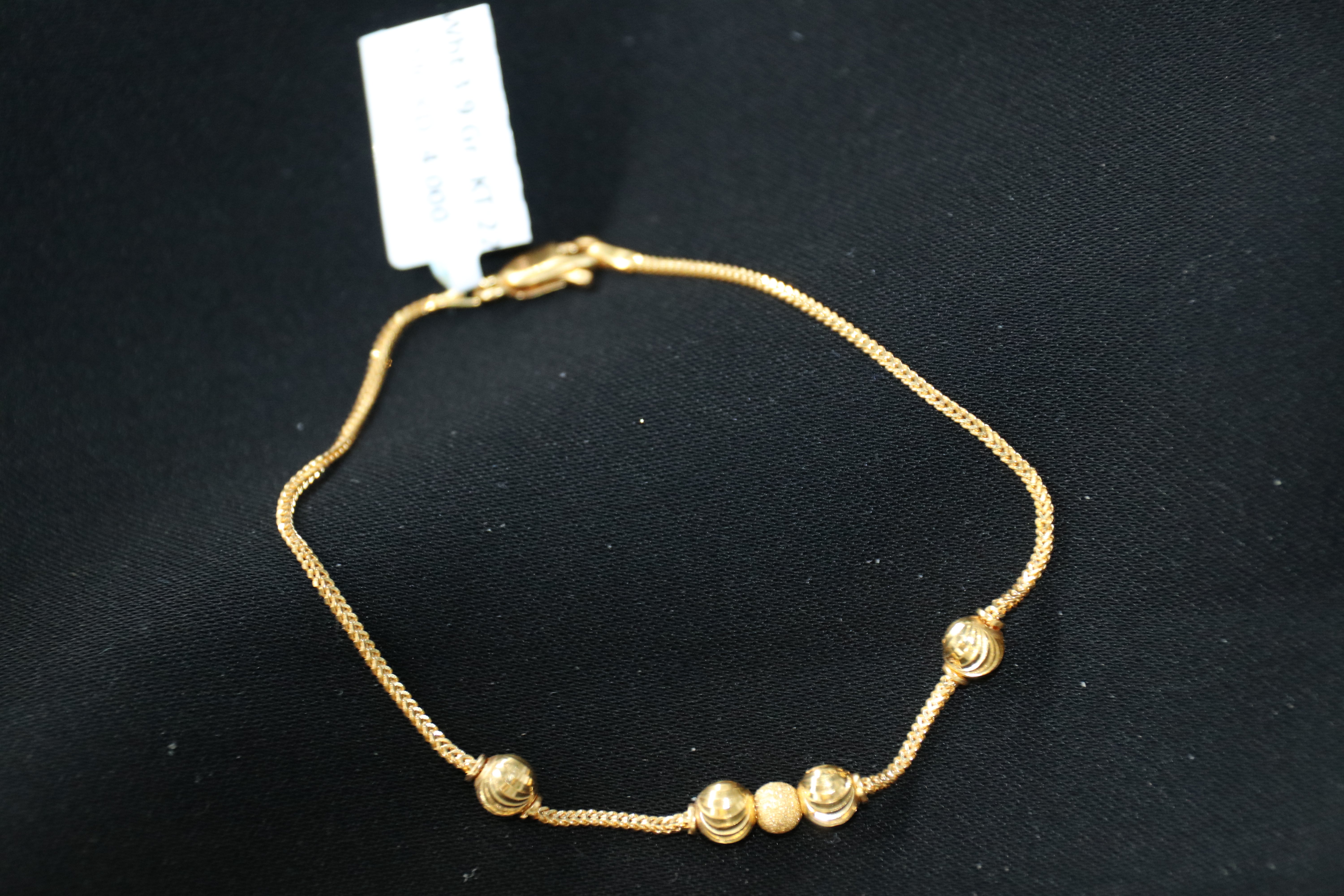 Gold bracelet with beads on a black background