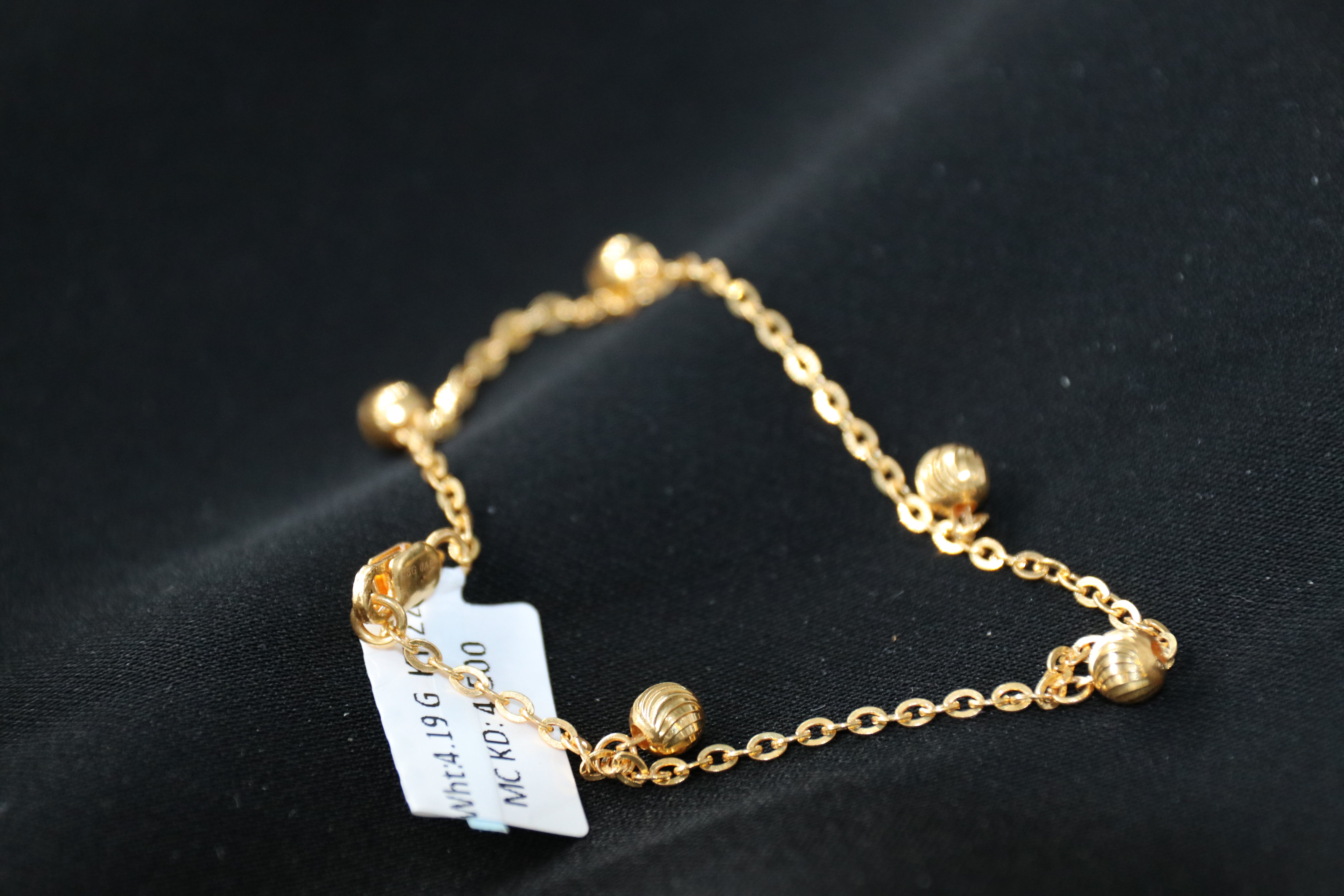 Gold bracelet with a tag on a black background