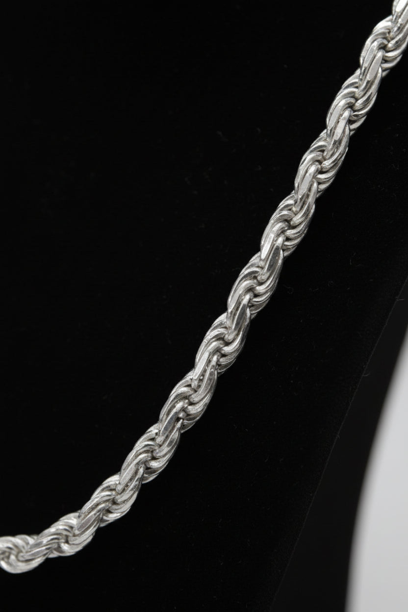 Silver rope chain on a black stand with a white background