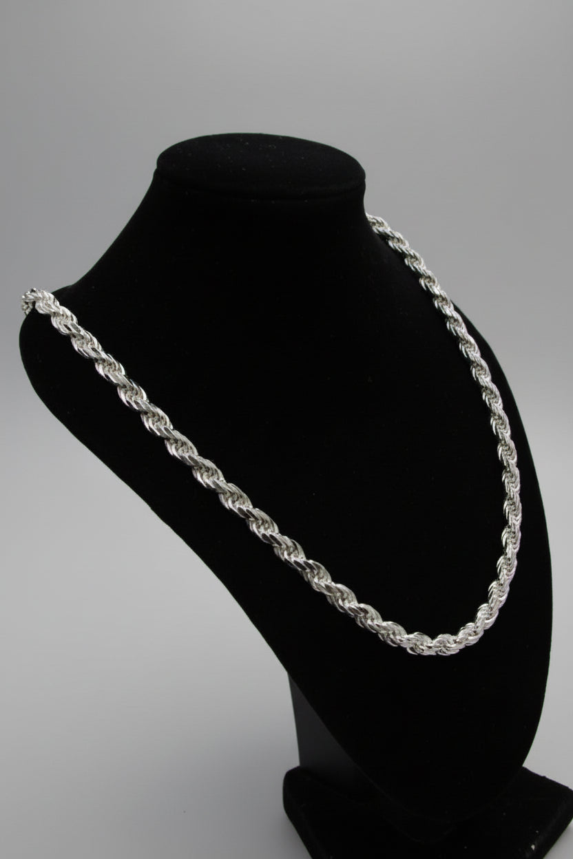 Silver chain necklace on a black stand against a neutral background