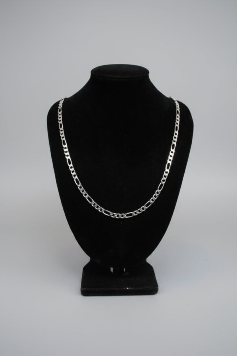 Silver chain necklace on a black stand against a neutral background