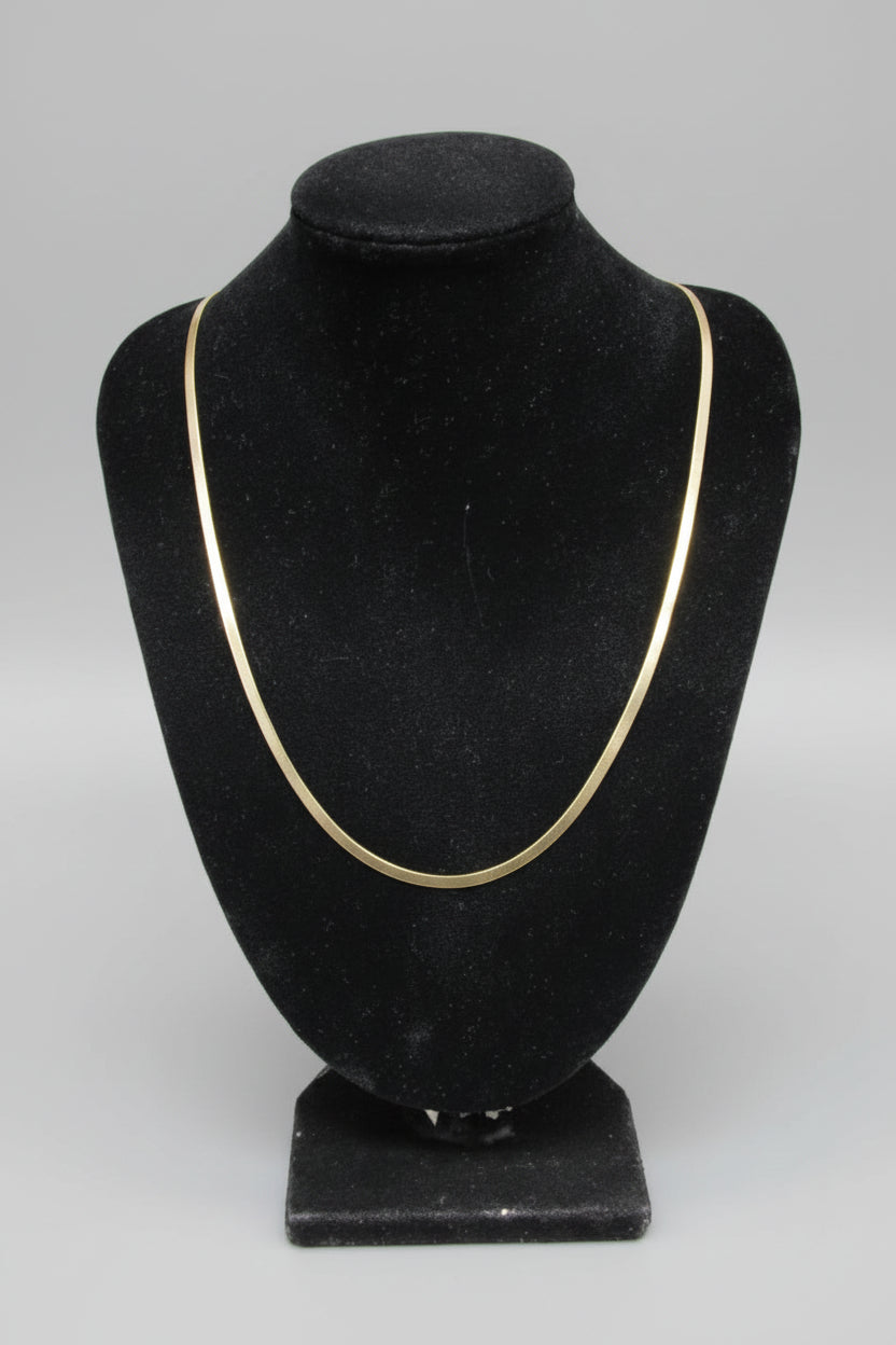 Gold necklace on a black velvet mannequin bust with a blurred background