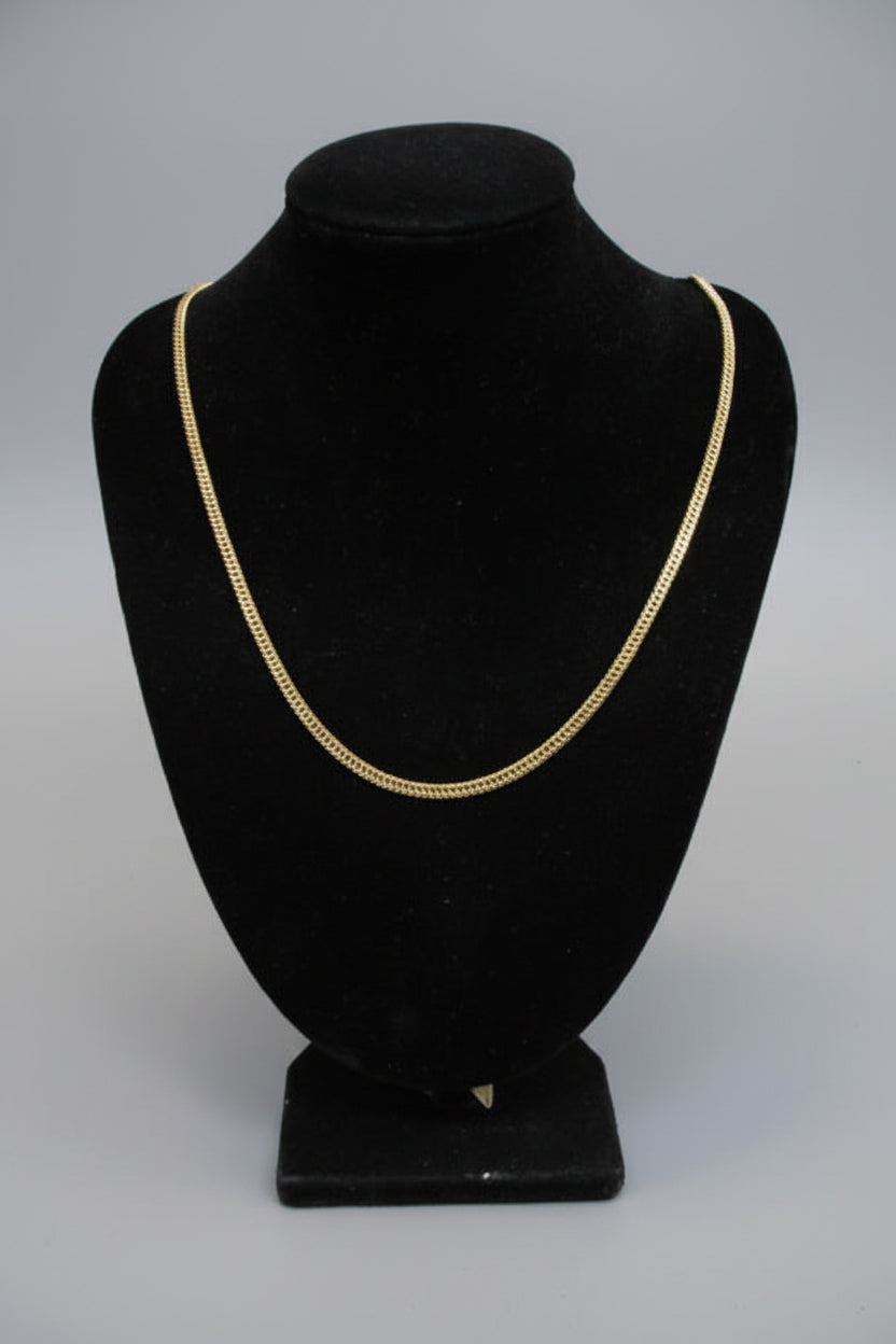 Black hat with gold trim on a stand against a marble wall.