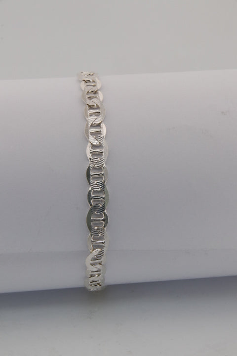 Silver ring on a white cylindrical stand against a light gray background