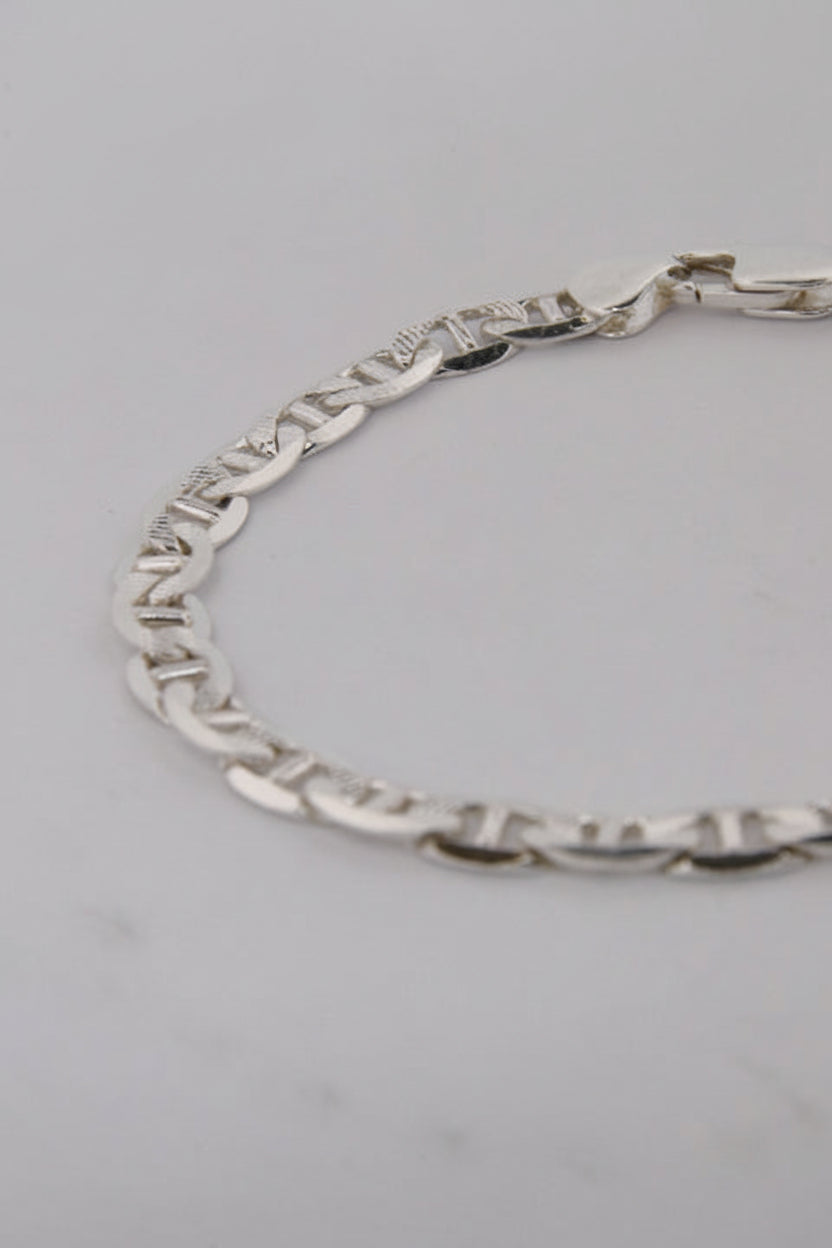 Silver chain bracelet on a light gray background