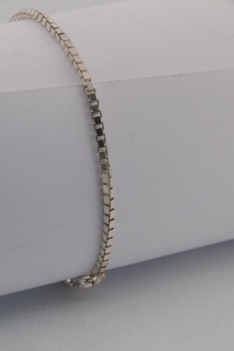Gold bracelet on a white mannequin arm