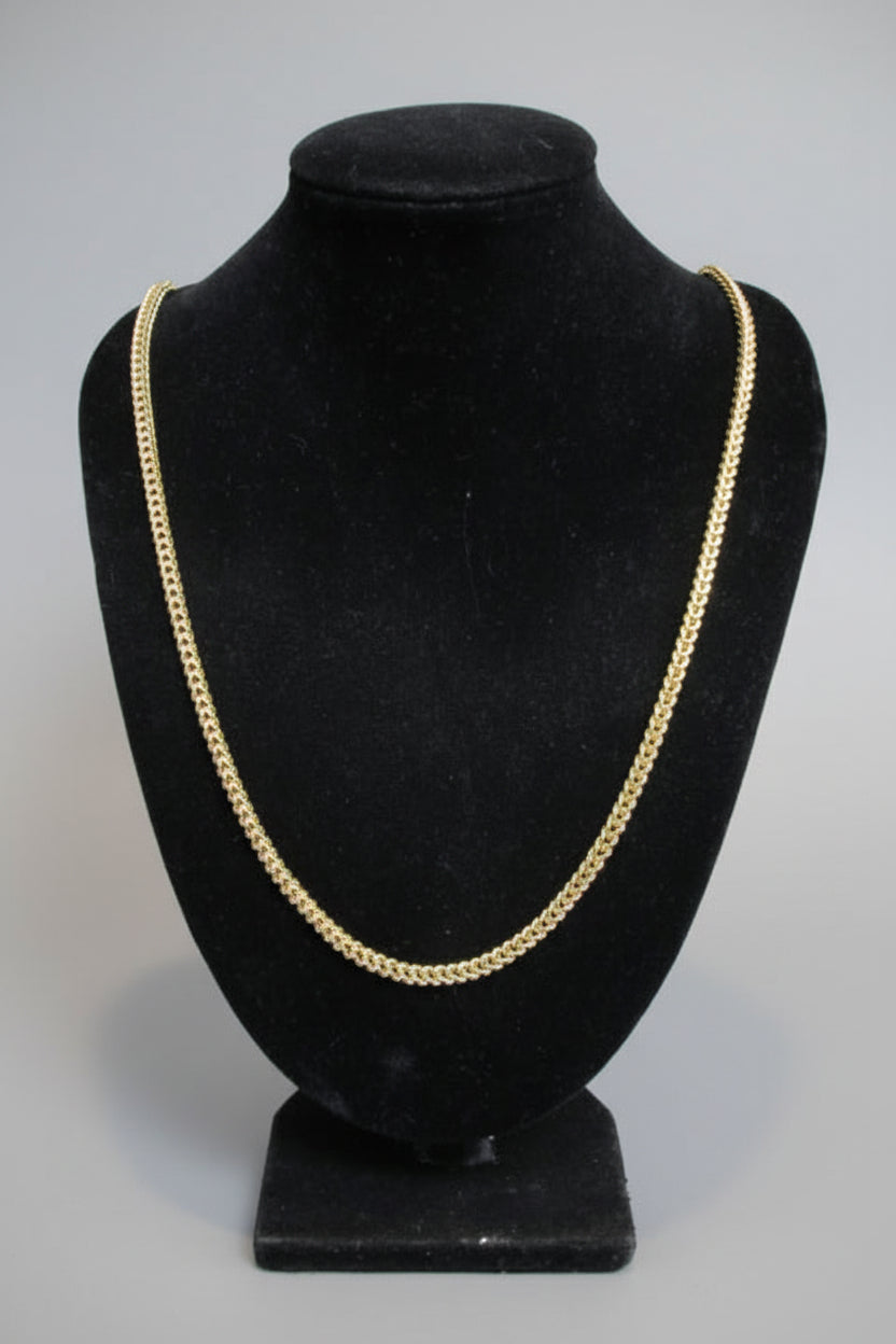 Black hat with gold trim on a mannequin head against a neutral background