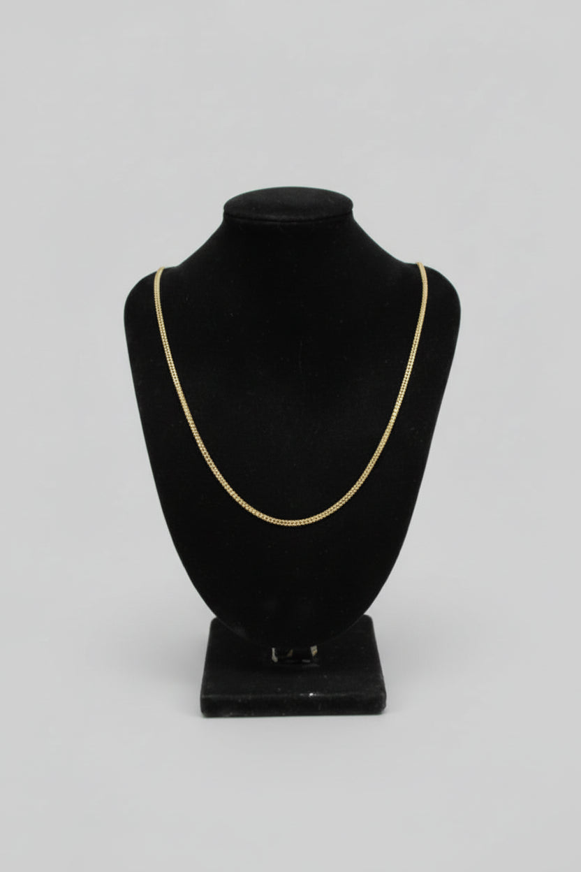 Black bowler hat with gold trim on a mannequin head against a marble wall.