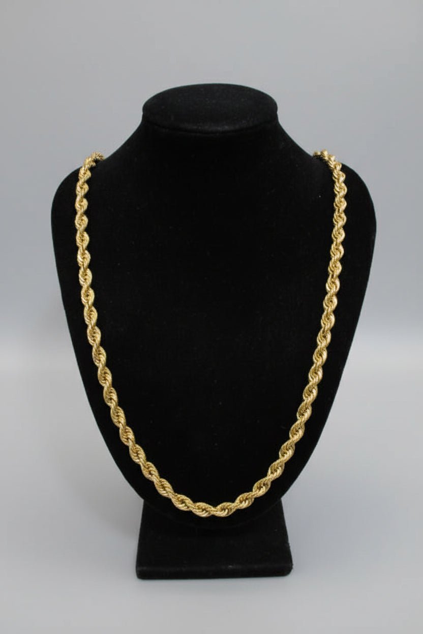 Gold chain on a black velvet stand against a marble background