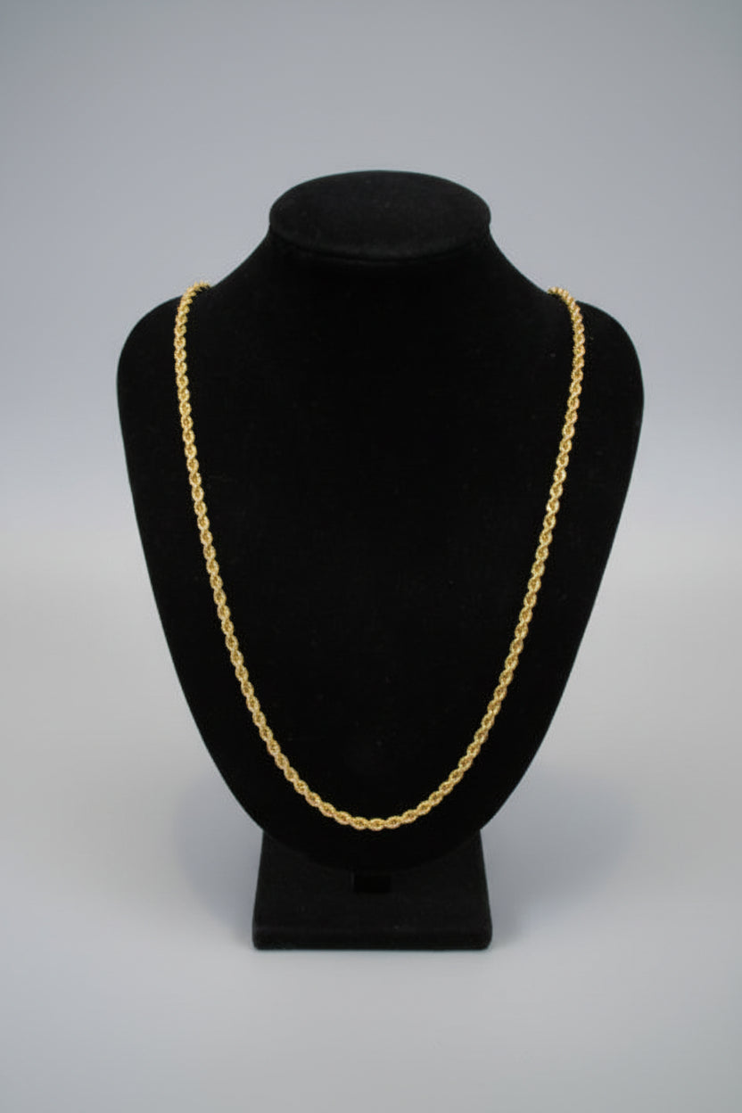 Black velvet bowler hat with gold chain detail on a white marble surface