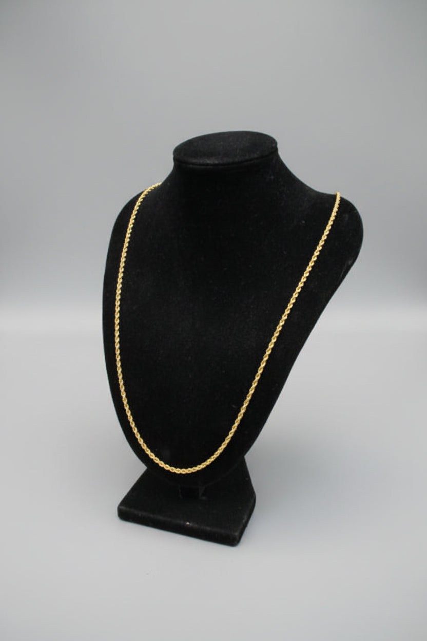 Black headgear with gold trim on a stand against a light background