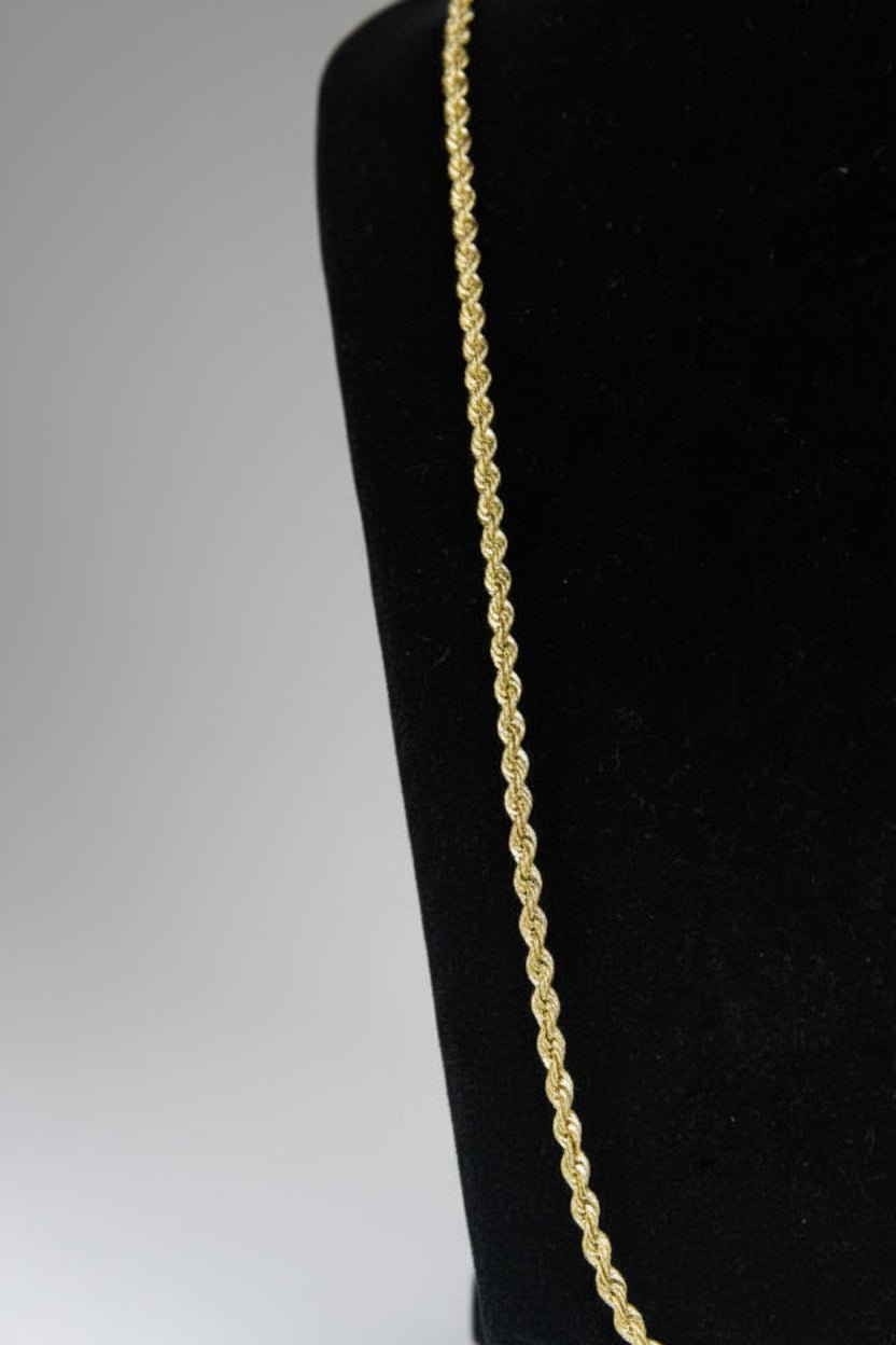 Gold rope chain on a black cushion with a white background