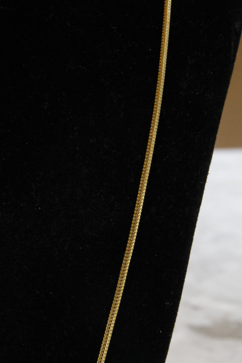 Close-up of a black fabric with a gold thread running through it.