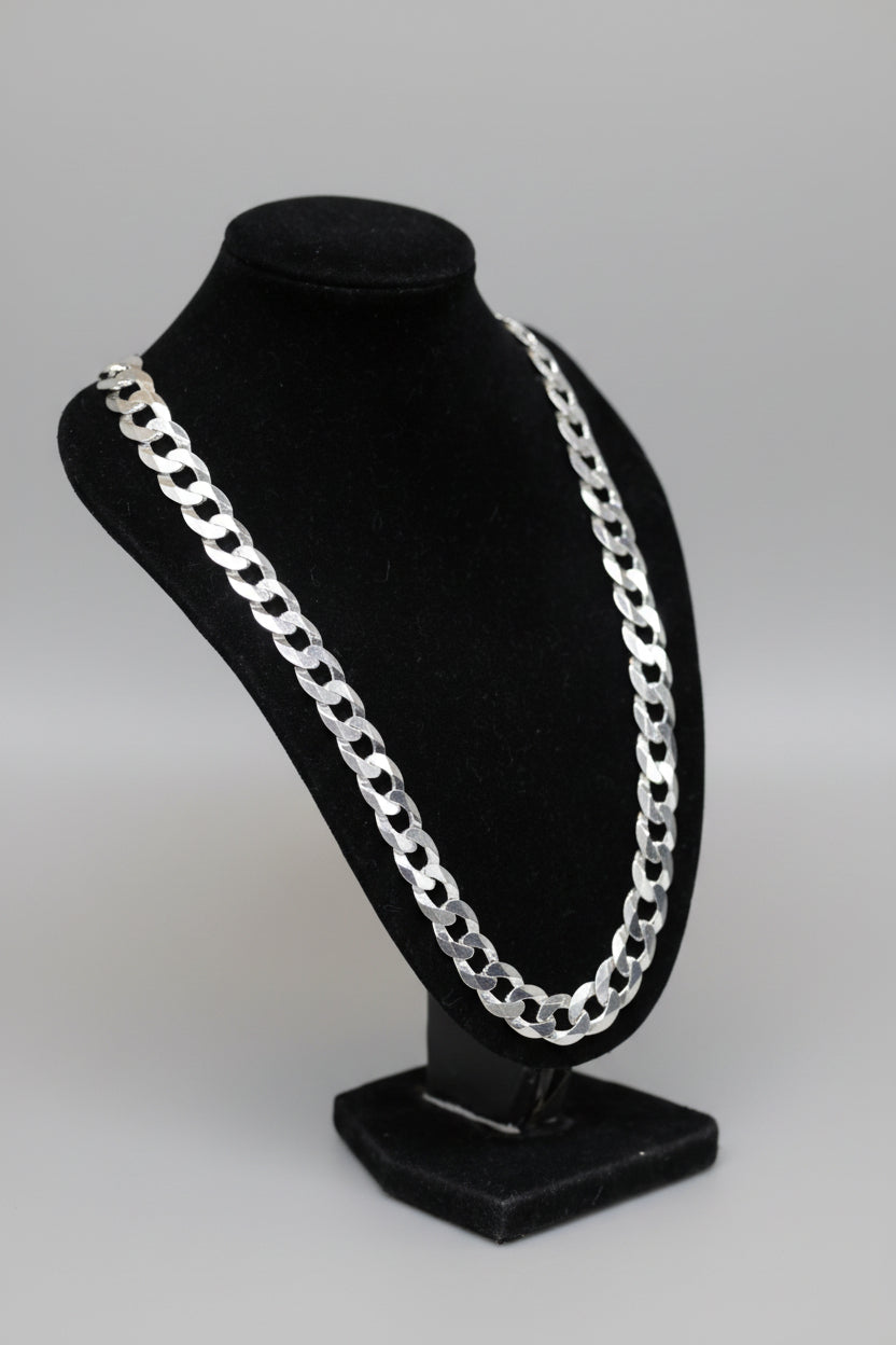 Silver chain necklace on a black bust against a neutral background