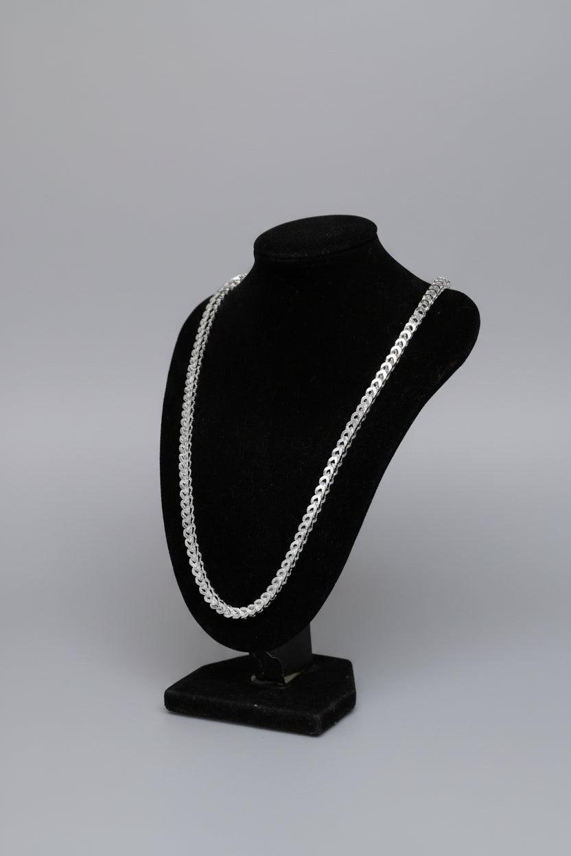 Silver chain necklace on a black stand with a blurred background