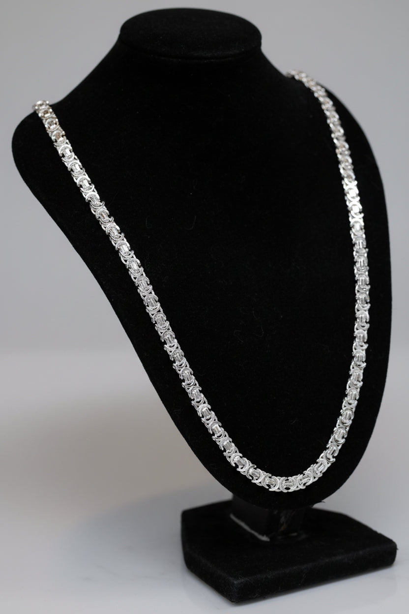 Silver necklace on a black jewelry stand with a blurred background