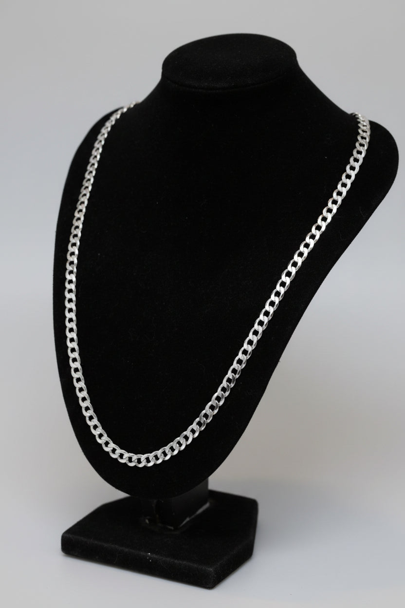Silver chain necklace on a black jewelry stand with a blurred background