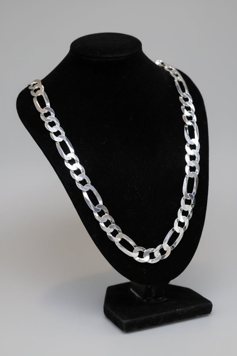 Silver chain necklace on a black mannequin bust against a marble surface.