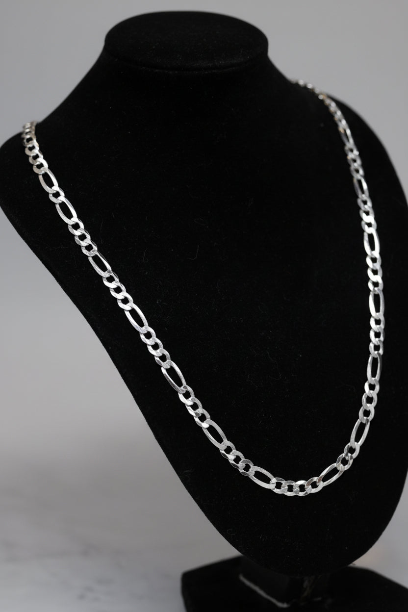 Silver chain necklace on a black mannequin bust with a blurred background