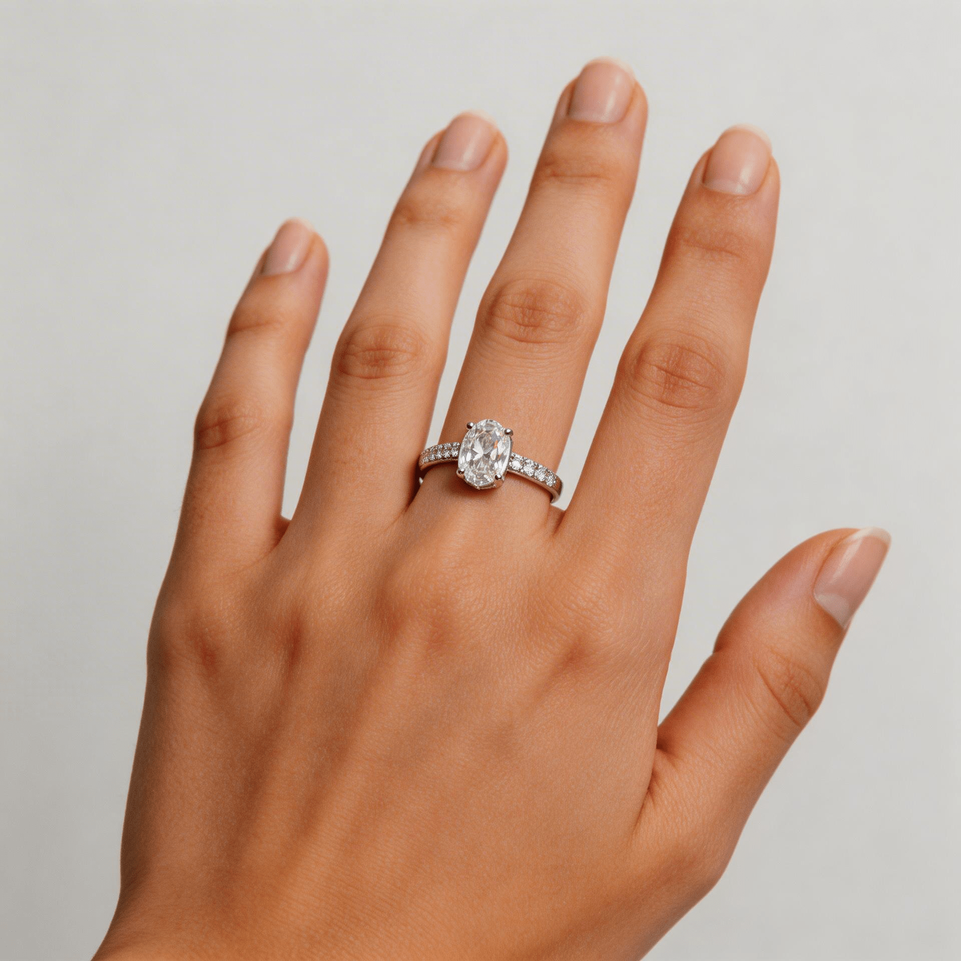 Hand wearing a diamond ring on a neutral background