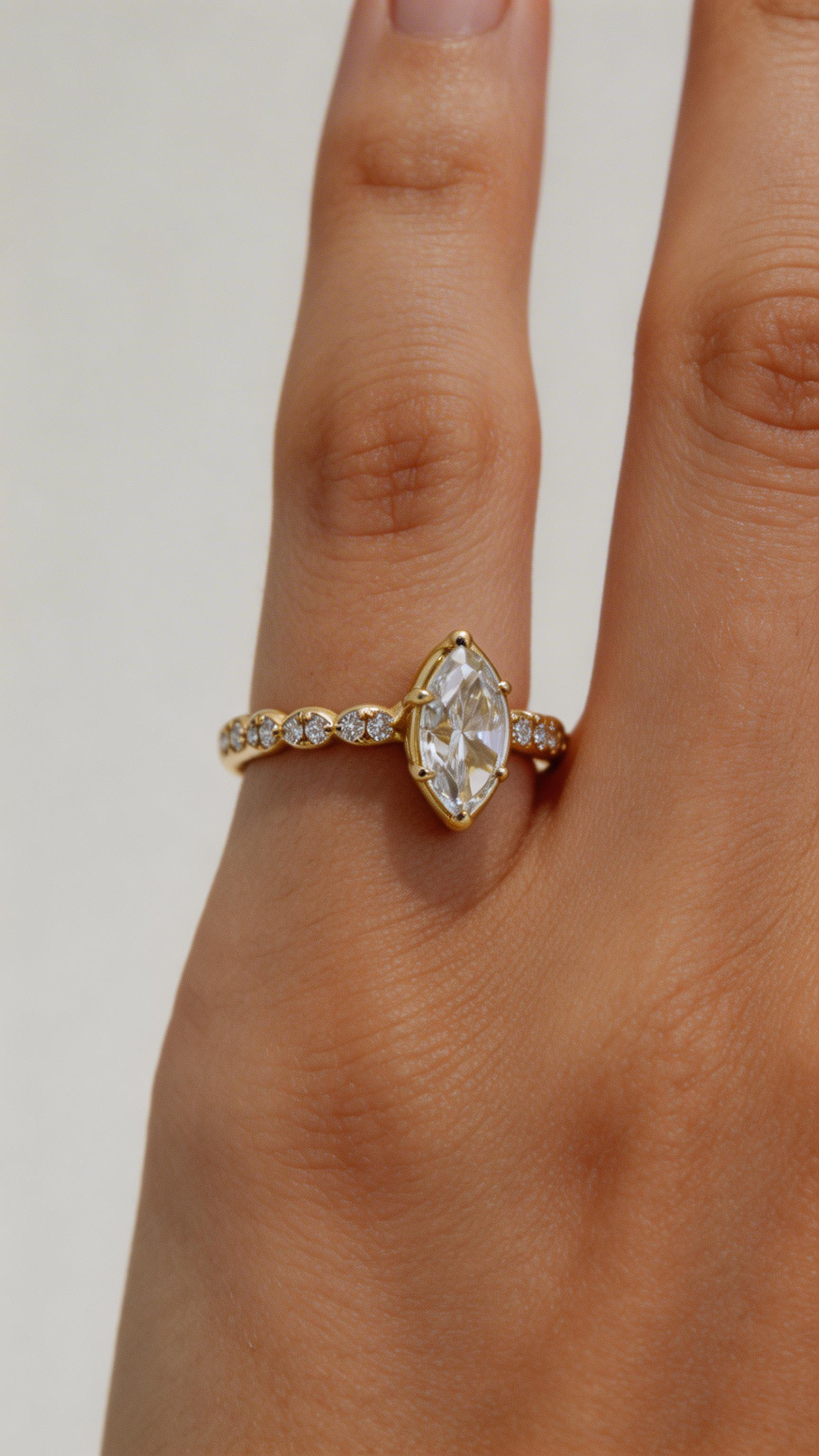 Gold ring with a large diamond on a finger against a neutral background