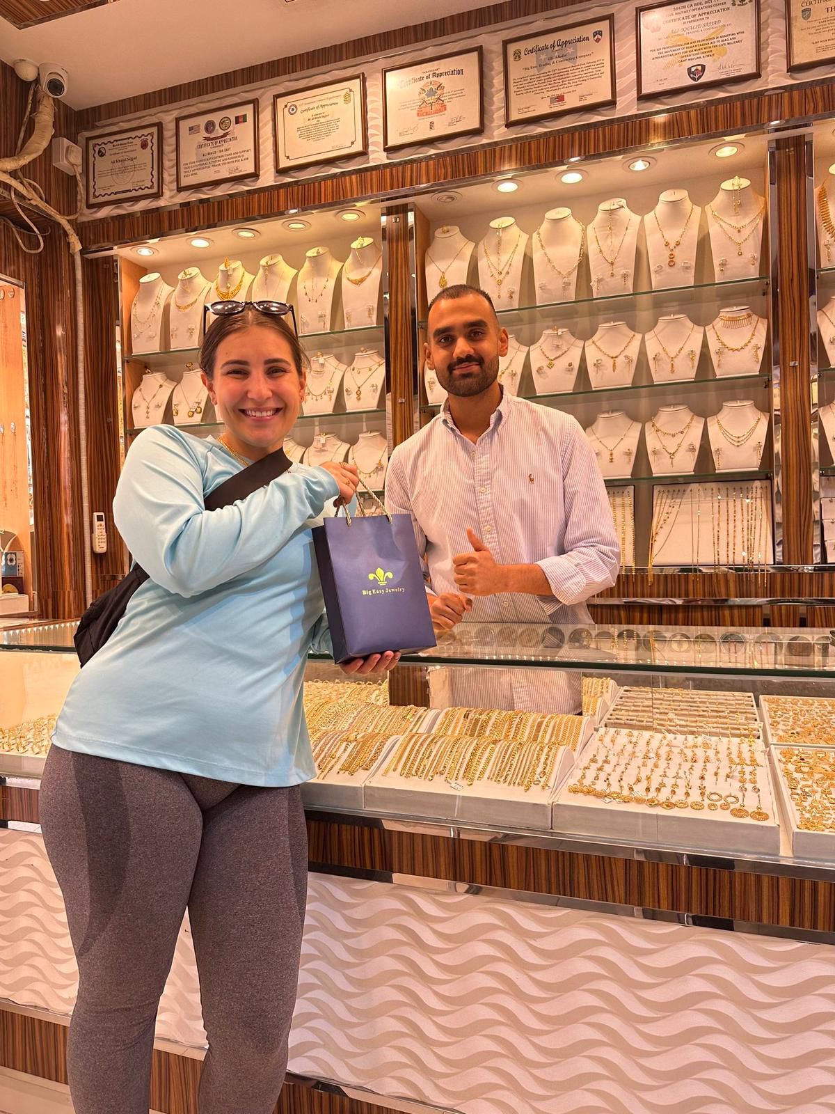 Woman holding a purple bag in front of a jewelry store display with a man.