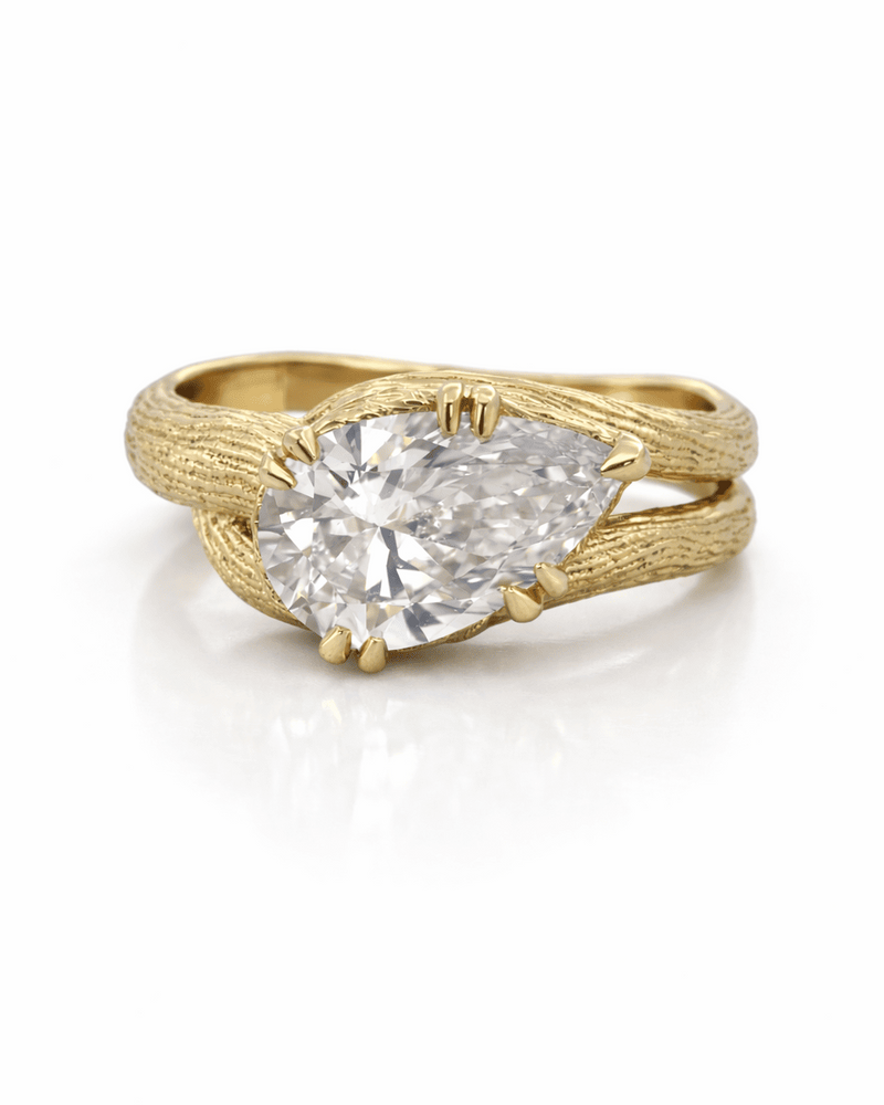 Gold ring with a pear-shaped diamond on a white background